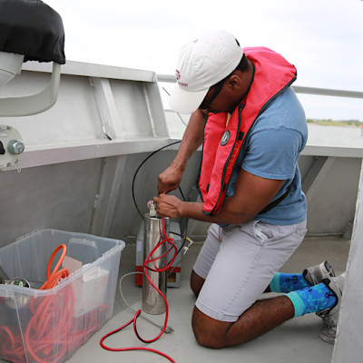 A student on a research vessel fills a small vial with water
