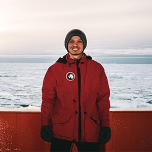 A man in a red jacket and beanie at sea