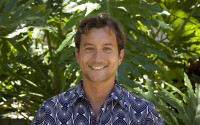 Profile of a smiling man surrounded by plants