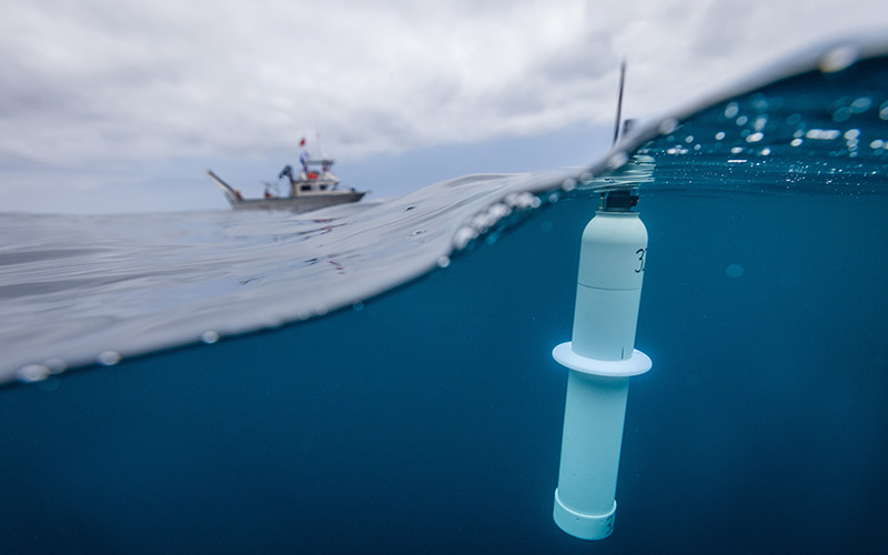 Argo float in the water in front of of research vessel Bob and Betty Beyster.