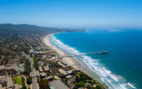 A aerial view of a college campus, a pier, and the Pacific Ocean