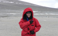 A woman in a red jacket conducts research in Antarctica