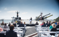 A man addresses the crowd at a pier dedication ceremony.
