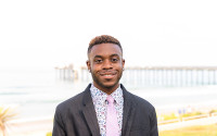 A portrait of a man with the ocean and a pier in the background