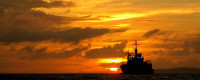 Ship silhouetted against a golden sunset.
