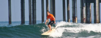 Surfer in front of Scripps Pier pilings