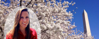 A woman smiles near a cherry blossum tree.