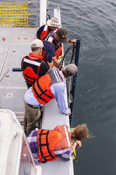 Five scientists test on a small research vessel test an ocean instrument.