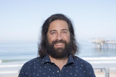 Profile photo of a bearded man near the ocean