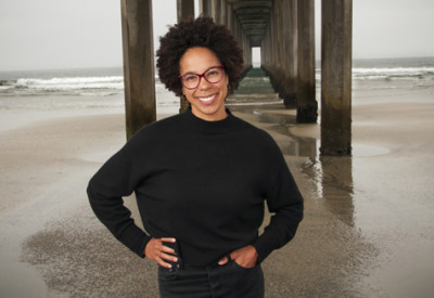 A woman in a black sweater stands under a pier
