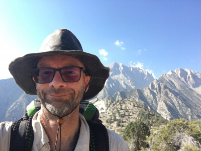 A man wearing a hat with mountains in the background.