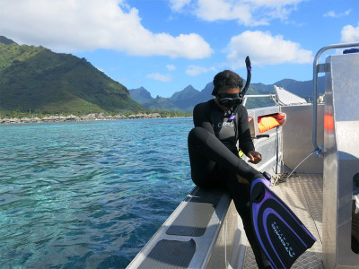 A woman in snorkeling gear gets ready to enter the ocean near a pristine island.