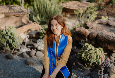 A woman with brown hair sits near a succulent garden