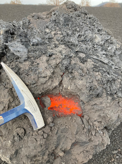 Geologist's hammer held next to red-hot spallation bomb.
