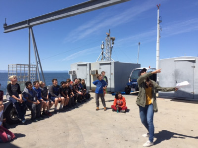 A woman leads a group of students on a pier tour.