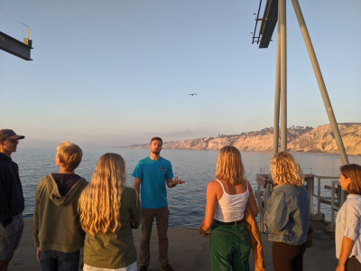A man leads a group of people on a pier tour.