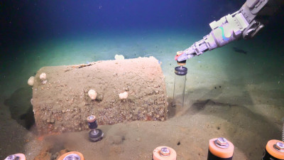 In an August 2021 expedition aboard Research Vessel Falkor, researchers use Remotely Operated Vehicle SuBastian to collect sediment push cores near a barrel on the seafloor. Credit: Schmidt Ocean Institute. 