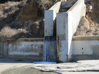 Water falling from a concrete structure built into a slope.
