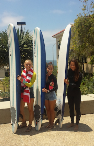 Three interns each holding a surfboard