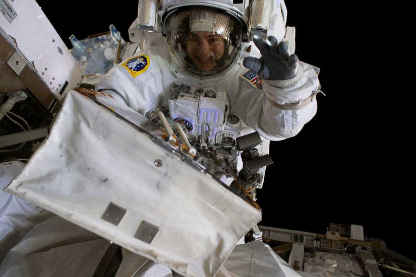 An astronaut waves while conducting a spacewalk