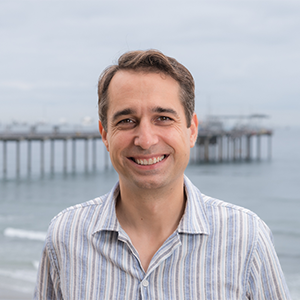 Portrait of a smiling man outdoors near the ocean and a pier