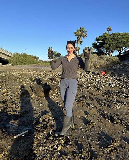 A woman at the bay holds oysters in gloved hands