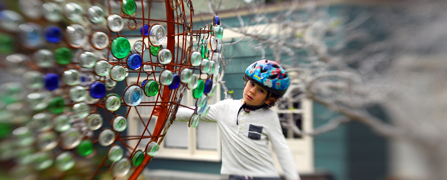 Young boy spins an outdoor art installation.