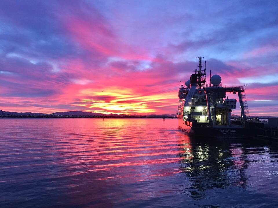 Research vessel Sally Ride at dock in front of orange, red and purple sunset